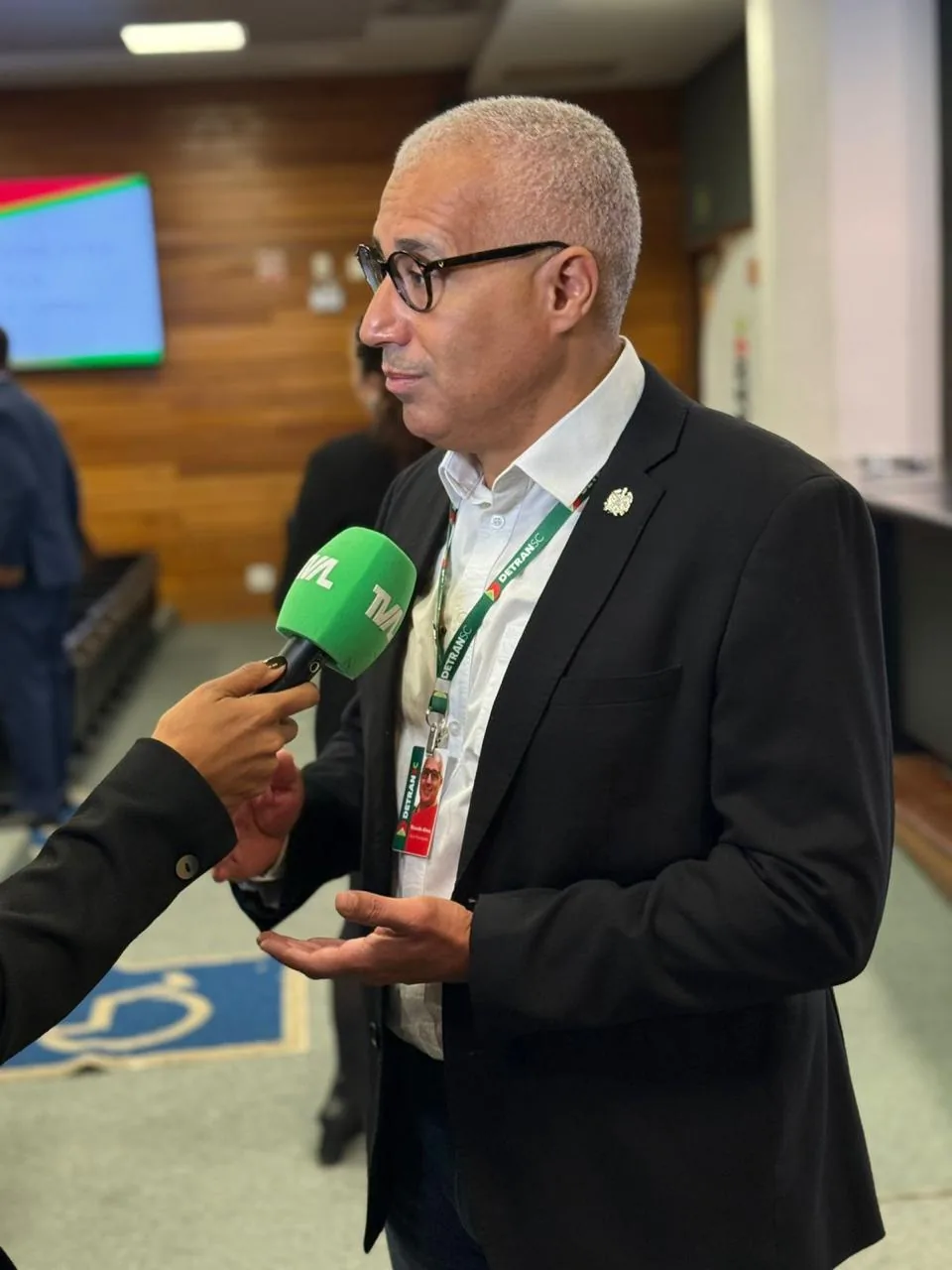 Ricardo Alves da Silva concedendo entrevista à imprensa com crachá do DETRAN-SC